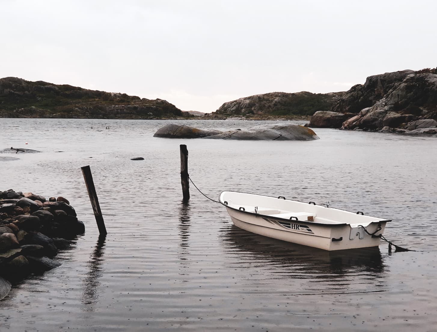 A solo boat docked in a rainy Swedish archipelago